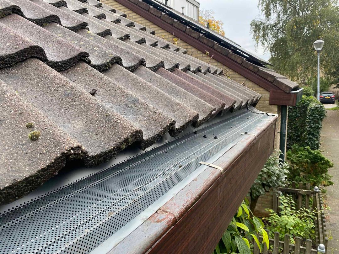 Dakgootroosters op maat gemonteerd langs een pannendak